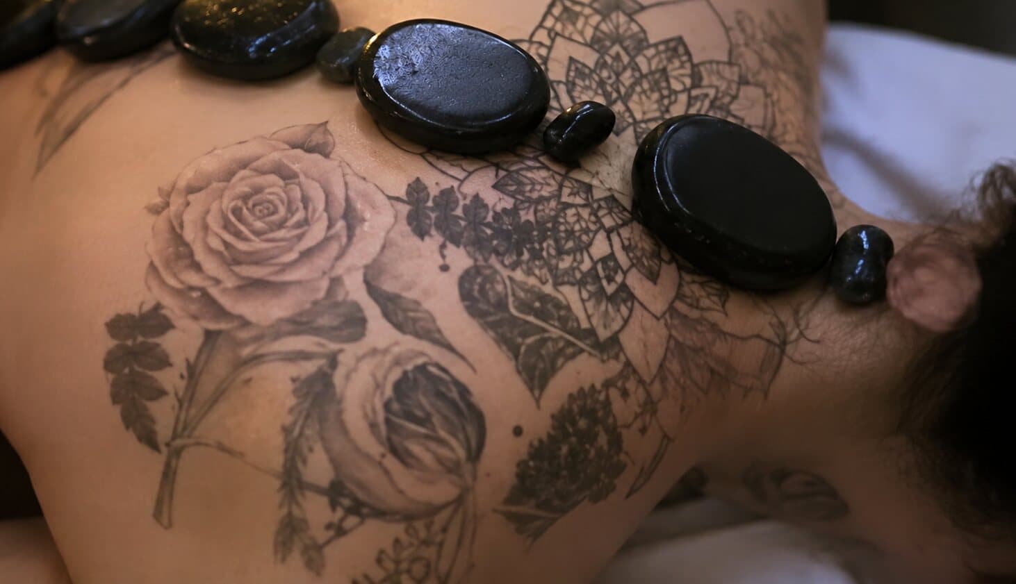 A hot stone massage in progress at The Peace Retreat, warm basalt stones resting along a client’s back